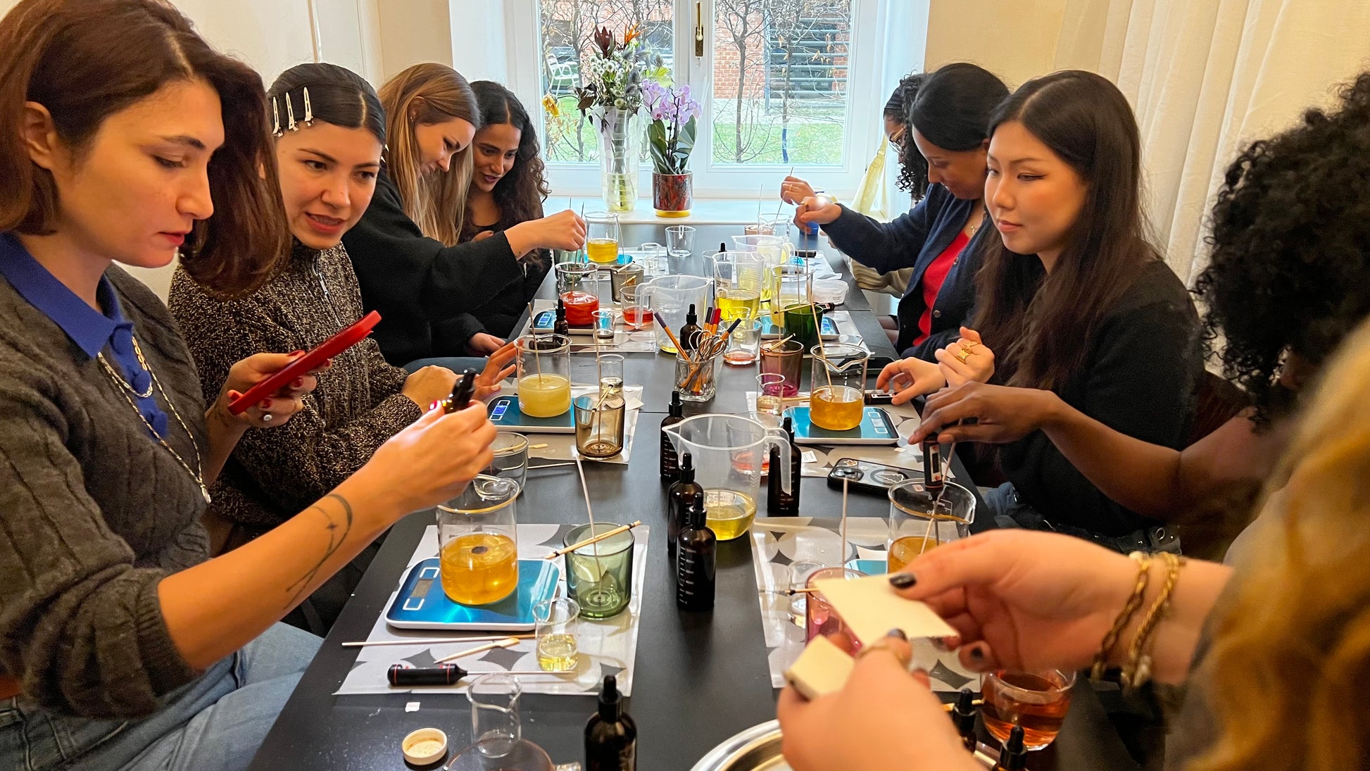 Group of people gathered around a table for a candle workshop, with drinks 